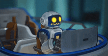 a robot with yellow eyes is sitting in front of a computer