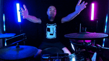 a man wearing a black shirt with the letter s on it is playing drums
