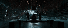 a group of people standing in a dark room with a lot of weapons hanging from the ceiling