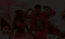 a man in a pink shirt flexes his muscles with a woman in a pink bikini