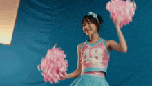 a cheerleader wearing a number 48 jersey is holding pink pom poms