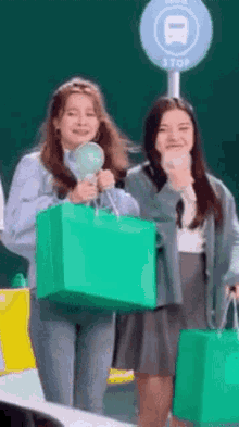 two women carrying shopping bags and a bus stop sign