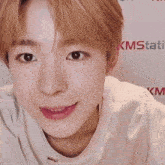 a young man is smiling in front of a kmstati banner