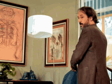 a man with a beard stands in front of a lamp in a living room