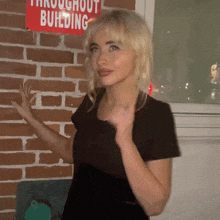 a woman stands in front of a brick wall with a red sign that says throughout building