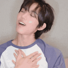a young man with his eyes closed and his hands on his chest .