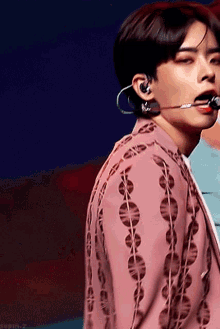 a close up of a person wearing a pink jacket and earbuds