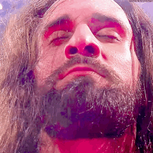 a man with long hair and a beard is looking up at the camera .