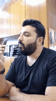 a man with a beard is smoking a cigar while sitting at a table