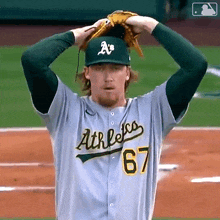 a baseball player for the a's adjusts his glove