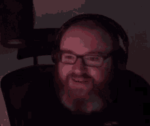 a man with a beard and glasses is wearing headphones and pointing up