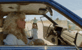 a woman is sitting in a car with a prada bag on the dash