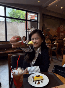 a woman is sitting at a table with a plate of food and a cup of iced tea