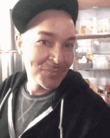 a man wearing a hat and a black hoodie smiles