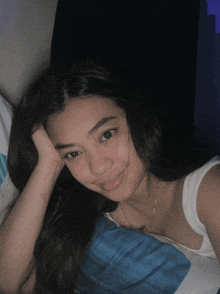 a young woman laying on a bed with her hand on her face
