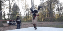 a wrestler is doing a flip over another wrestler in a ring .