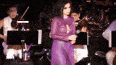 a woman in a purple dress sings into a microphone