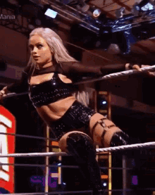 a woman in a wrestling ring with the word mania on the bottom left