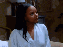 a woman wearing a white robe is sitting on a bed