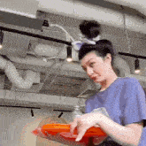 a woman in a blue shirt is holding a tray