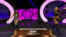 two female wrestlers on a stage with tayjay written on the bottom