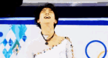a man is laughing while wearing a white dress and necklace .