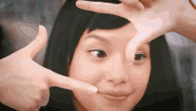 a young girl is making a face with her hands .