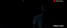 a man in a white shirt is standing in the dark looking at a firework display .