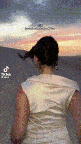 a woman in a white dress is standing in front of a sunset with a caption that says just a heart broke bitch