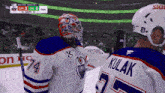 a hockey player wearing a number 74 jersey talks to another player