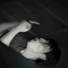 a man is laying on his back in the dark making a funny face