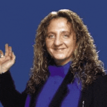 a woman with long curly hair is wearing a purple shirt