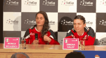 two women are sitting at a table with a sign that says simona halep on it
