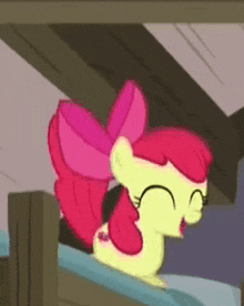 a cartoon pony with a pink bow is sitting on top of a bed .