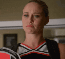 a cheerleader wearing a red white and black uniform is holding a racket