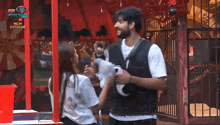 a man and woman are standing next to each other in front of a sign that says bigg boss