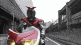 a person in a red and black costume is riding a red and white motorcycle
