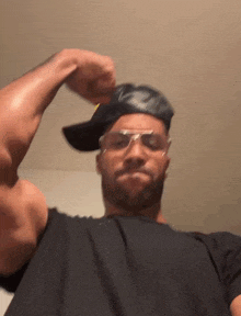 a man wearing a hat and sunglasses is flexing his arm