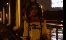 a girl wearing a harley quinn shirt is standing in a dark alleyway
