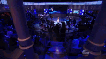 a woman stands on a stage in front of a screen that says abc on it