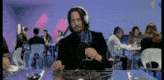 a man wearing headphones sits at a table with a plate of food and a glass of wine