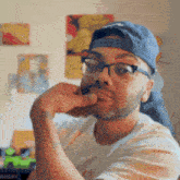 a man wearing glasses and a baseball cap has his hand on his chin