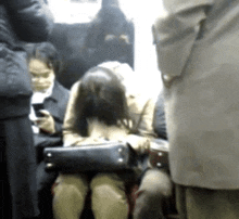 a woman sits in a crowd of people looking at her cell phone