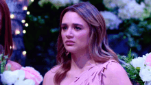 a woman in a pink dress is sitting in front of flowers and lights