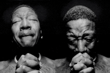 a black and white photo of two men praying