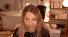 a woman is smiling and looking at the camera while sitting in a chair in front of a bookshelf .