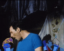 a man in a blue shirt with a mustache is standing in front of a curtain