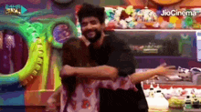 two men are hugging each other in front of a sign that says jiocinema .