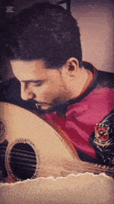 a man playing a guitar with a pink shirt that says ' al-ahli ' on it