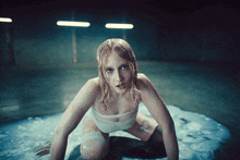 a woman is kneeling in a pool of water
